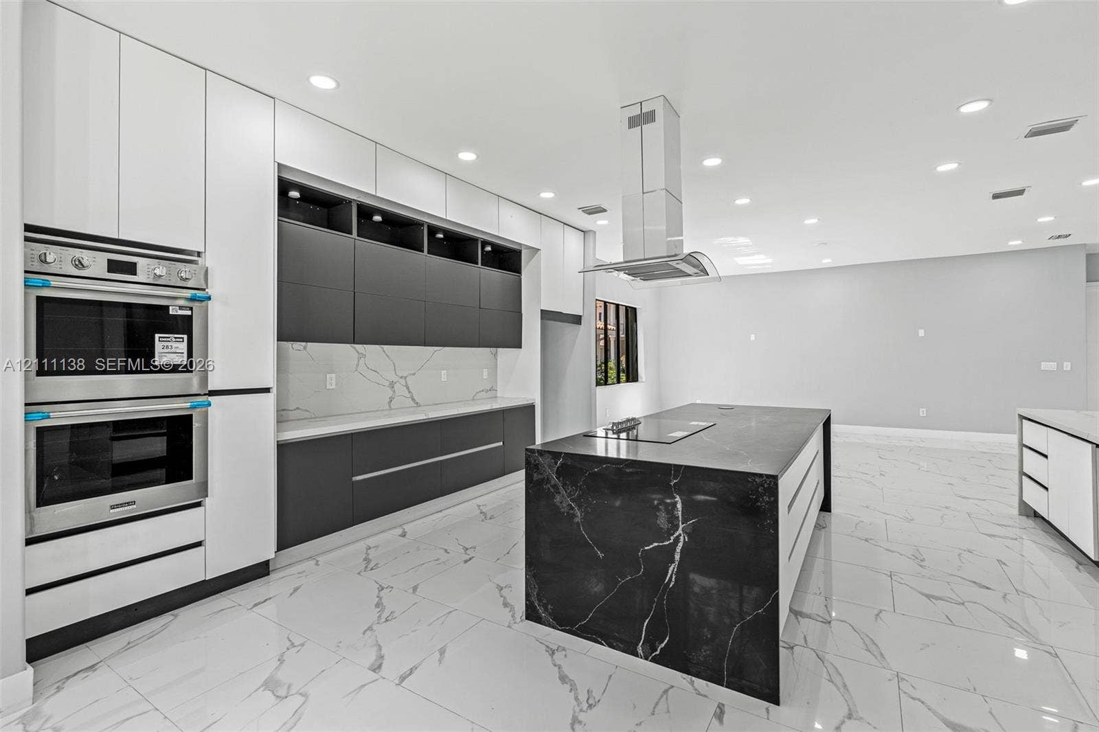 19363 SW 79th Avenue, Cutler Bay, FL 33157 Kitchen featuring flat-panel cabinetry, a waterfall-edge island with an integrated cooktop, quartz countertops with a veined pattern, a stainless steel double wall oven, and recessed lighting