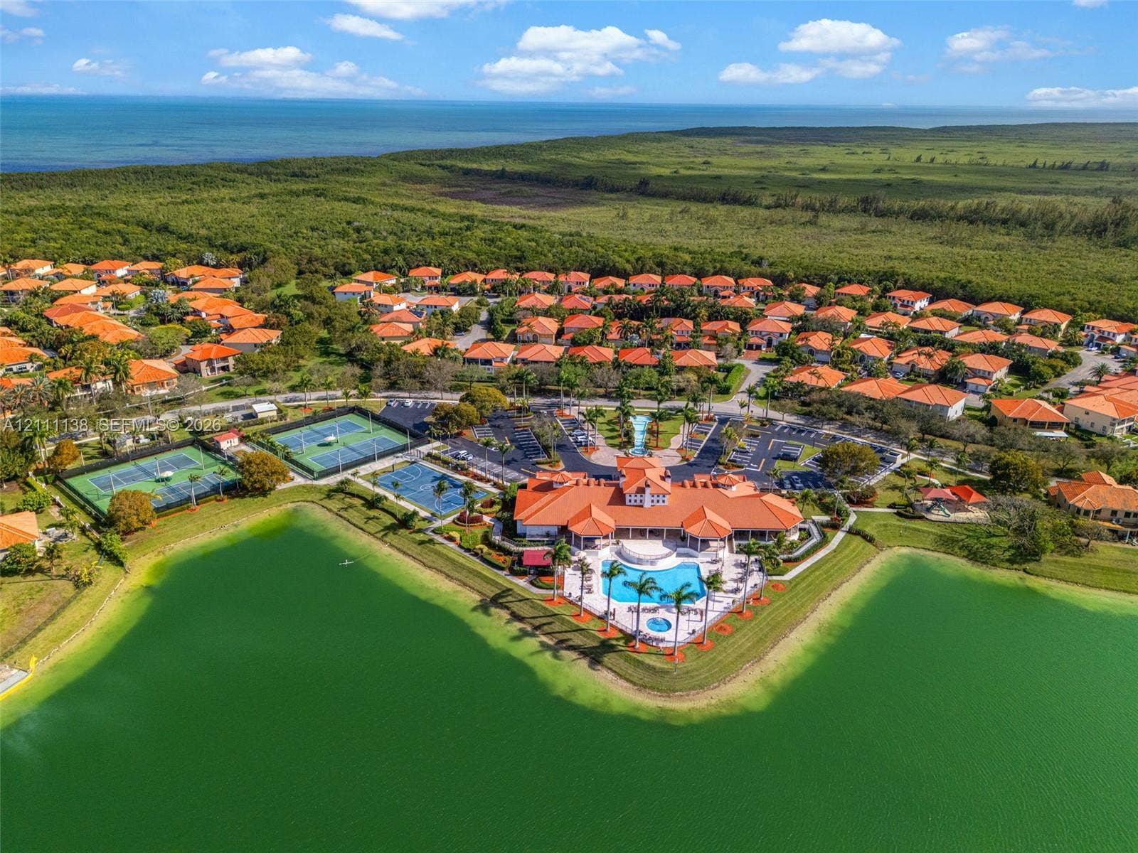 19363 SW 79th Avenue, Cutler Bay, FL 33157 Aerial perspective of a community clubhouse featuring a swimming pool, multiple tennis courts, shoreline access, and proximity to the coast