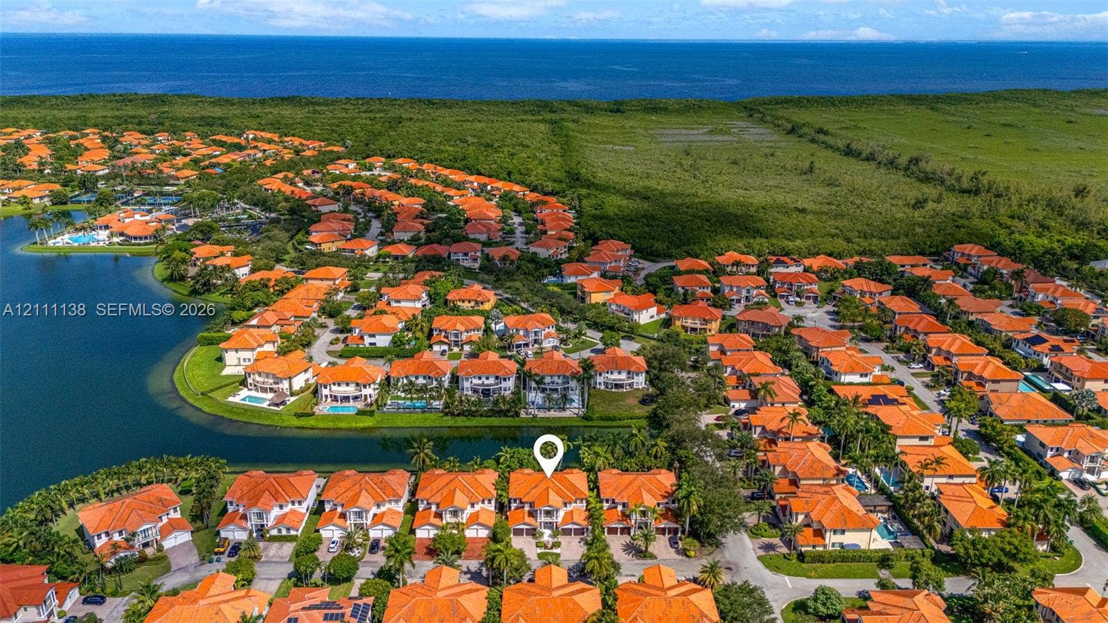 19363 SW 79th Avenue, Cutler Bay, FL 33157 Aerial perspective of a multi-level residence featuring a clay tile roof, paved driveway, and water frontage with bulkhead