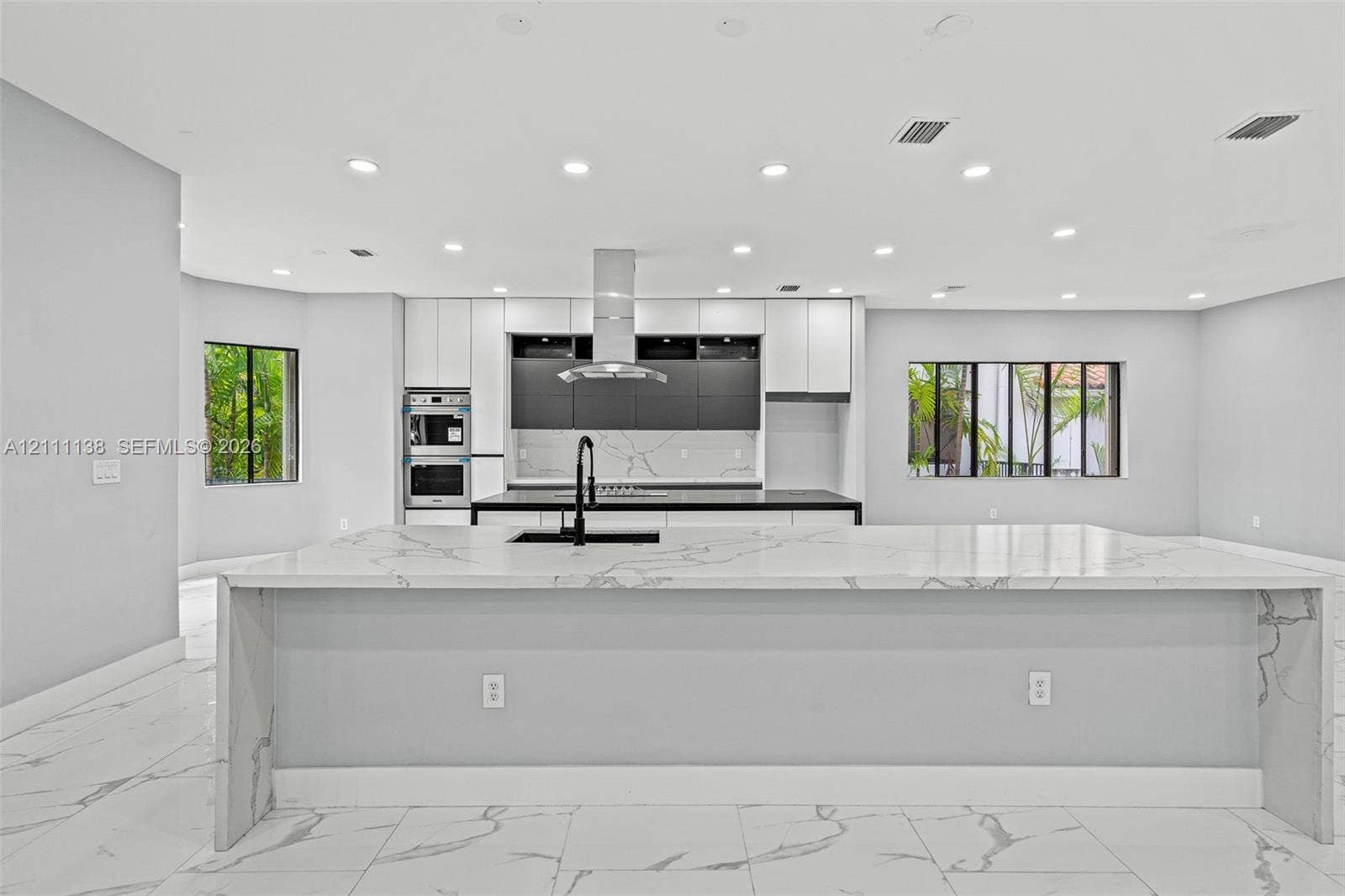19363 SW 79th Avenue, Cutler Bay, FL 33157 Kitchen featuring a large waterfall-edge island with stone-finish countertops, matte black faucet, integrated stainless steel double oven, two-tone cabinetry, and recessed lighting