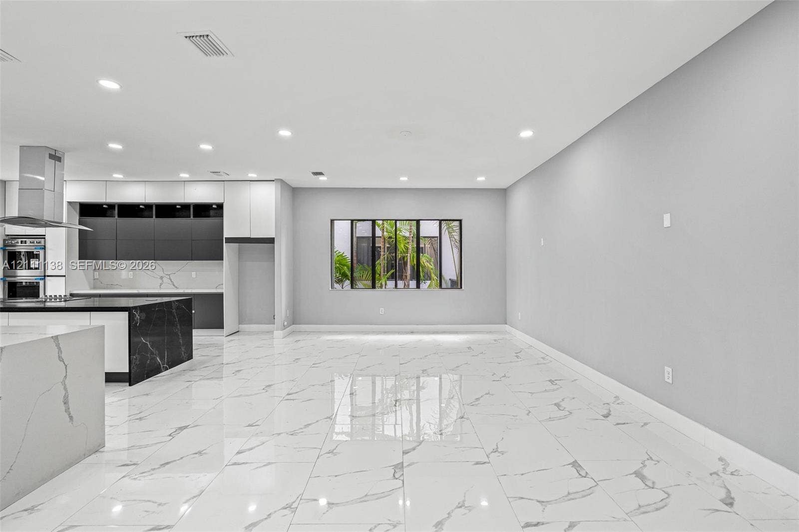 19363 SW 79th Avenue, Cutler Bay, FL 33157 Open-concept interior featuring large-format polished stone-finish flooring, two-tone cabinetry with contrasting stone-finish countertops, stainless steel wall oven, and recessed lighting