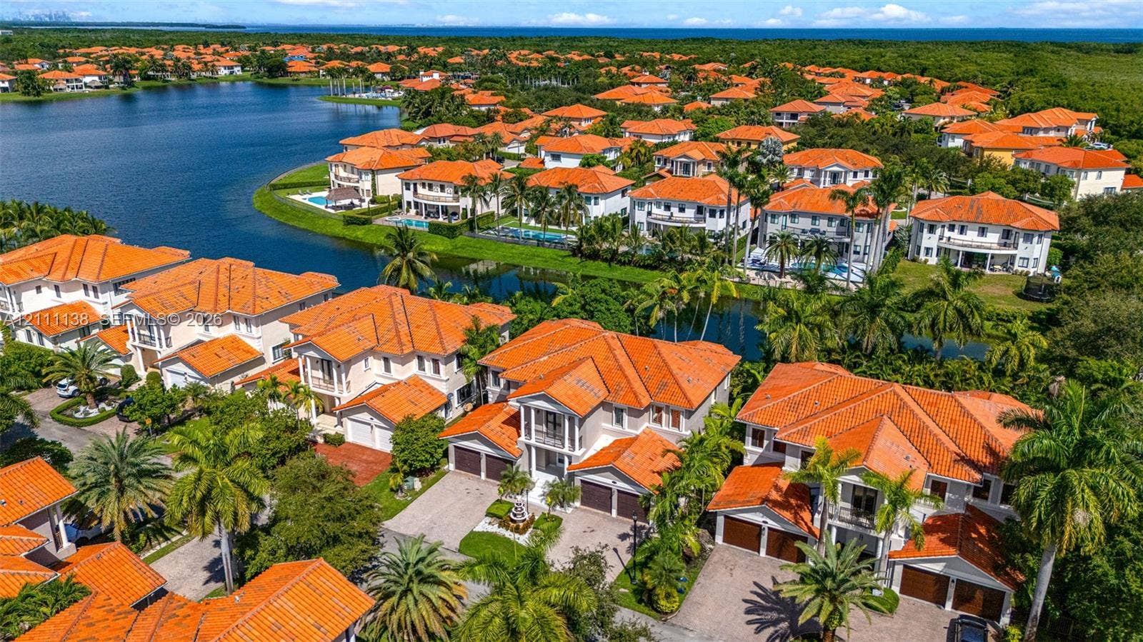 19363 SW 79th Avenue, Cutler Bay, FL 33157 Aerial perspective featuring multi-story residences with terracotta-style tile roofing, paved driveways, multi-car garages, and mature palm landscaping situated along a waterfront canal