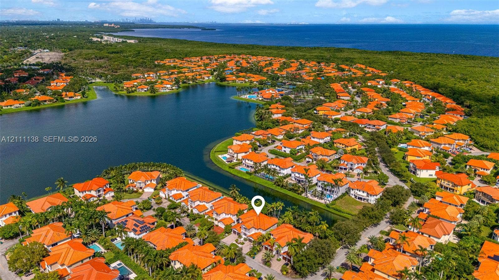 19363 SW 79th Avenue, Cutler Bay, FL 33157 Aerial perspective of a multi-story residence with a tile roof situated in a waterfront community featuring extensive lake frontage and mature palm trees