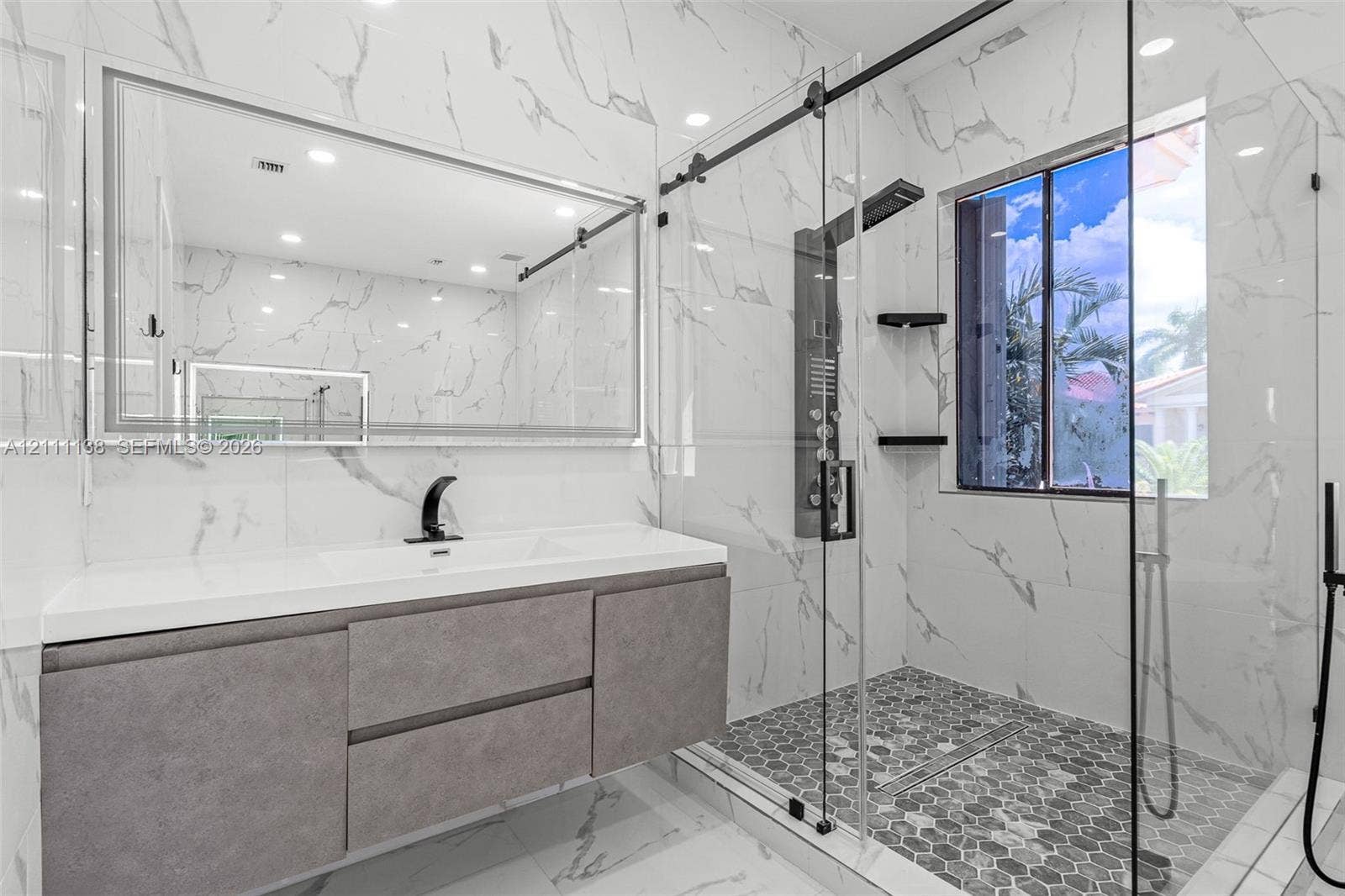 19363 SW 79th Avenue, Cutler Bay, FL 33157 Floating vanity with integrated sink, floor-to-ceiling large-format tile walls, walk-in shower with glass enclosure, multi-head shower panel, and hexagonal tile flooring