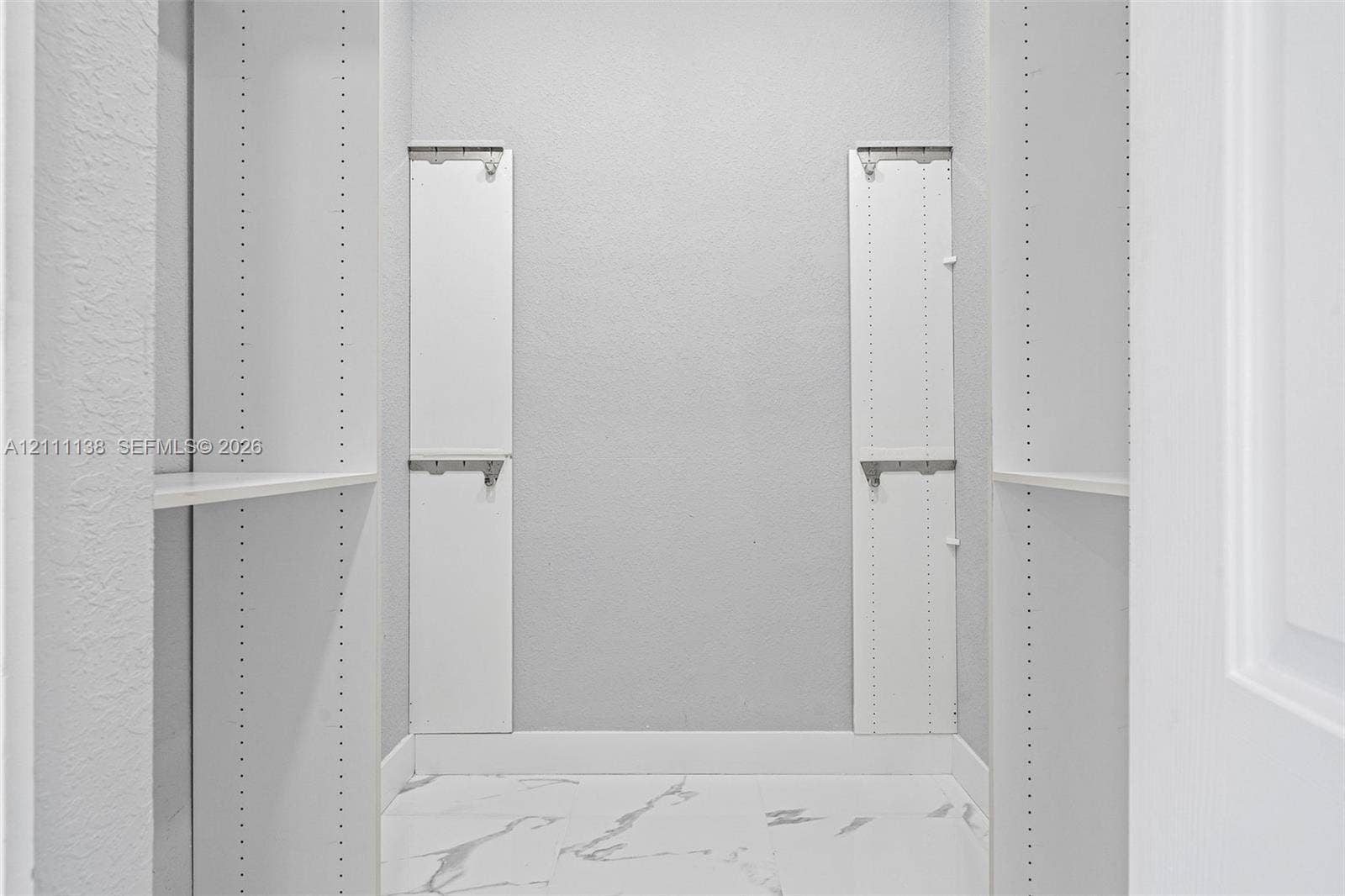 19363 SW 79th Avenue, Cutler Bay, FL 33157 Storage space featuring white built-in shelving units, adjustable support tracks, and white stone-patterned flooring