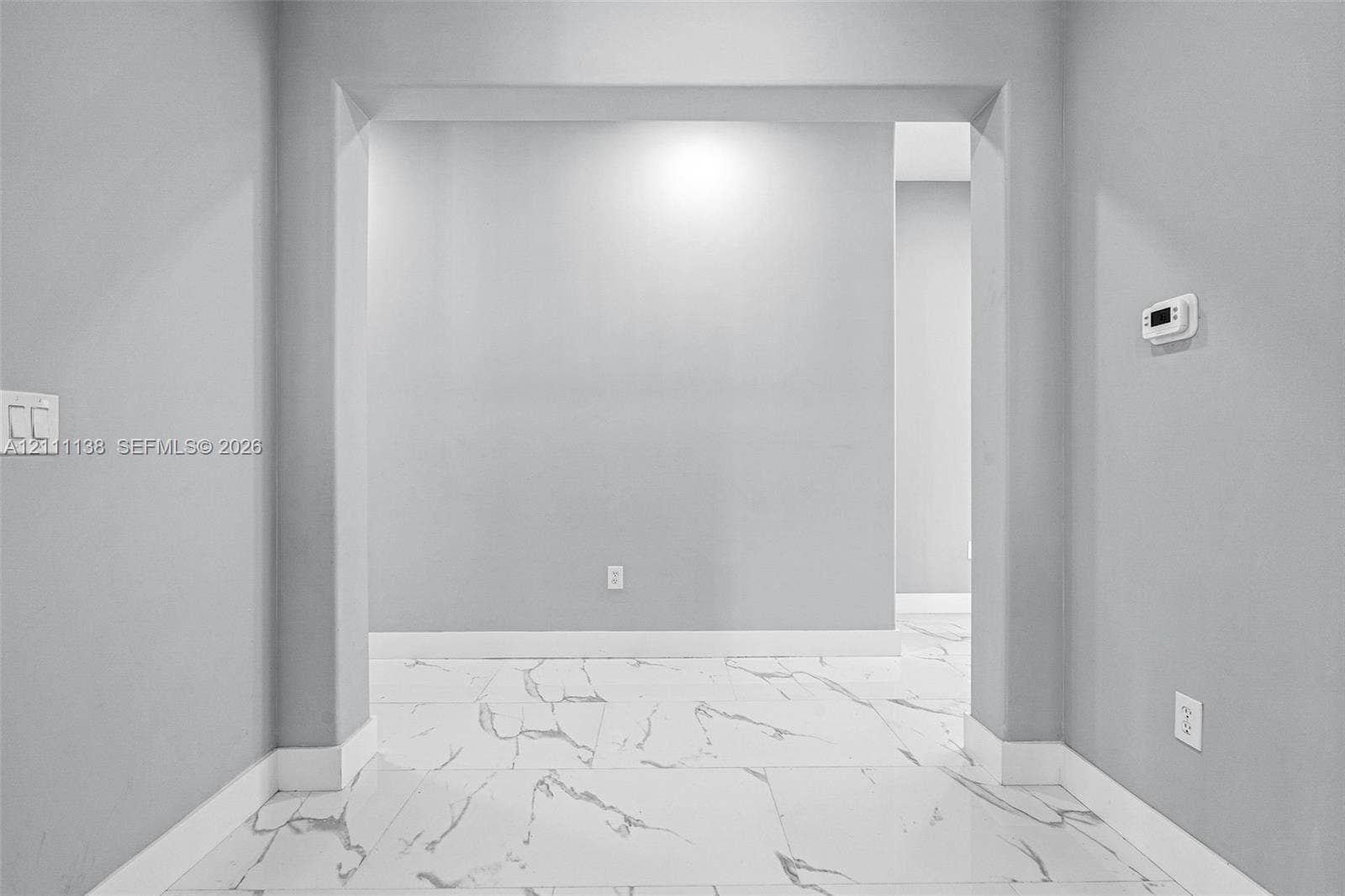 19363 SW 79th Avenue, Cutler Bay, FL 33157 Large-format tile flooring featuring high-contrast veining, neutral grey wall paint, and a wide architectural archway