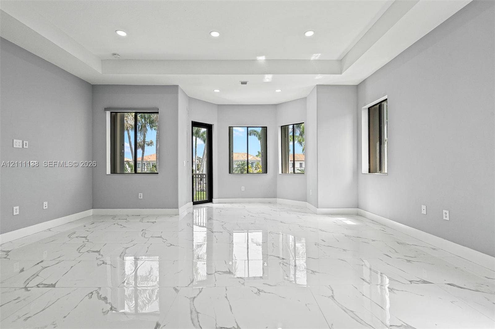 19363 SW 79th Avenue, Cutler Bay, FL 33157 Living space featuring large-format tile flooring with a veined pattern, tray ceiling with recessed lighting, and multiple windows
