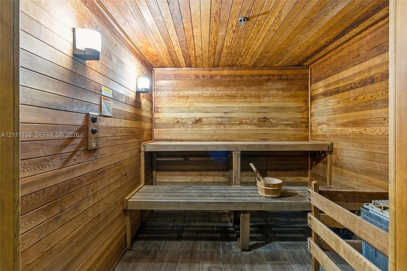 19363 SW 79th Avenue, Cutler Bay, FL 33157 Sauna featuring wood paneling, multi-level built-in bench seating, recessed wall-mounted lighting, and a protective heater guard