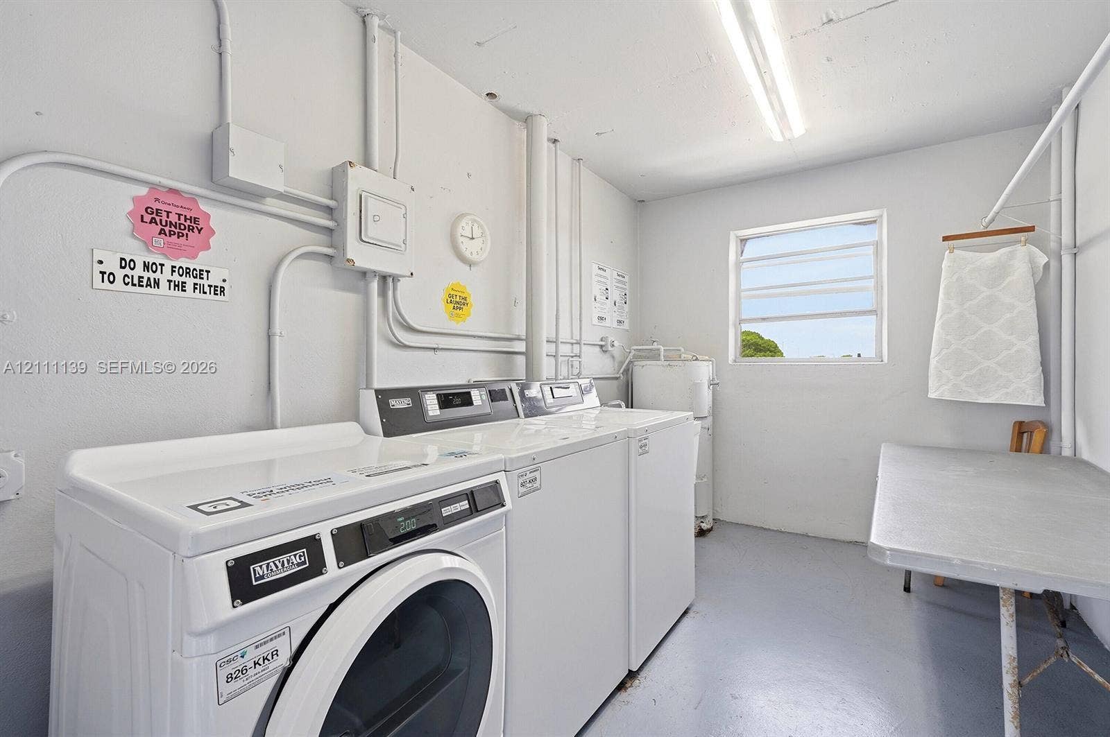 1333 E Hallandale Beach Boulevard, #236, Hallandale Beach, Hallandale Beach, FL 33009 Utility room featuring painted concrete flooring, a horizontal louvered window, and overhead fluorescent lighting