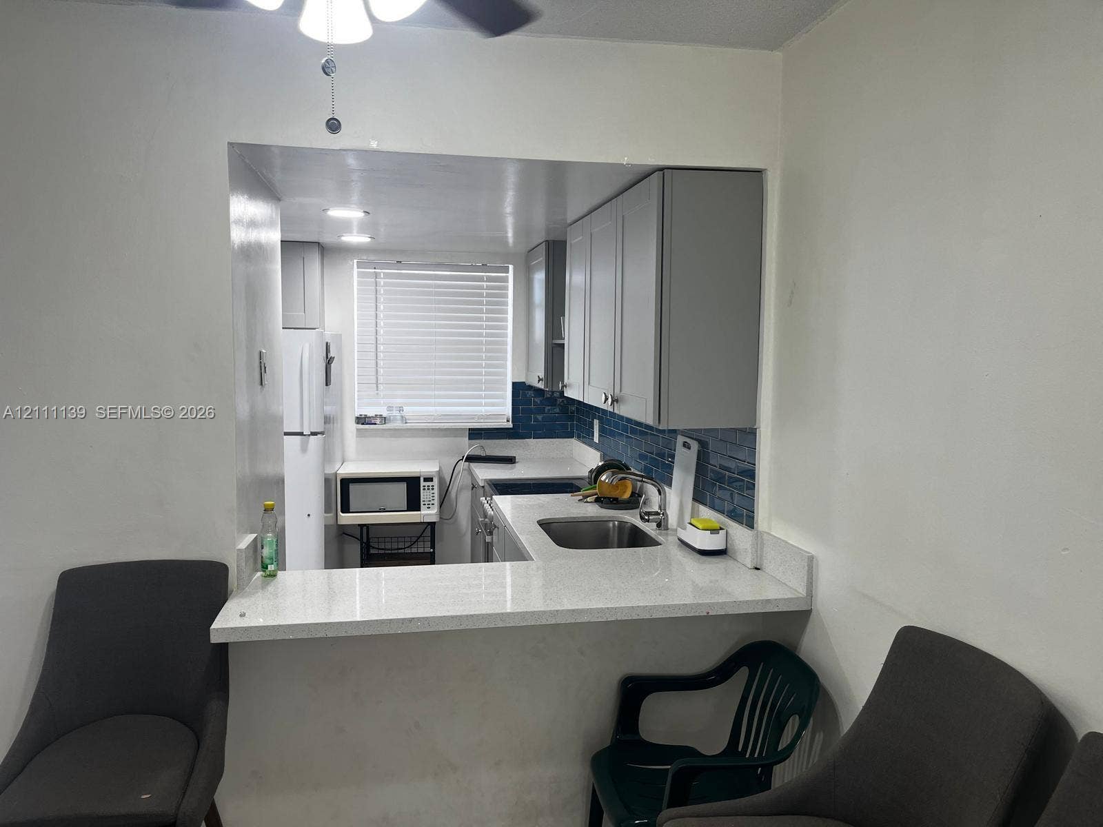 1333 E Hallandale Beach Boulevard, #236, Hallandale Beach, Hallandale Beach, FL 33009 Kitchen featuring light-colored cabinetry, stone-finish countertops, a stainless steel undermount sink, blue tile backsplash, and a breakfast bar