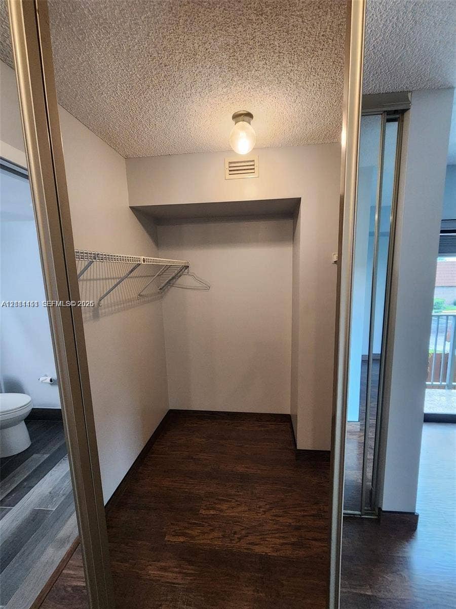Storage area featuring wood-finish flooring, sliding mirror-paneled doors, and wire shelving