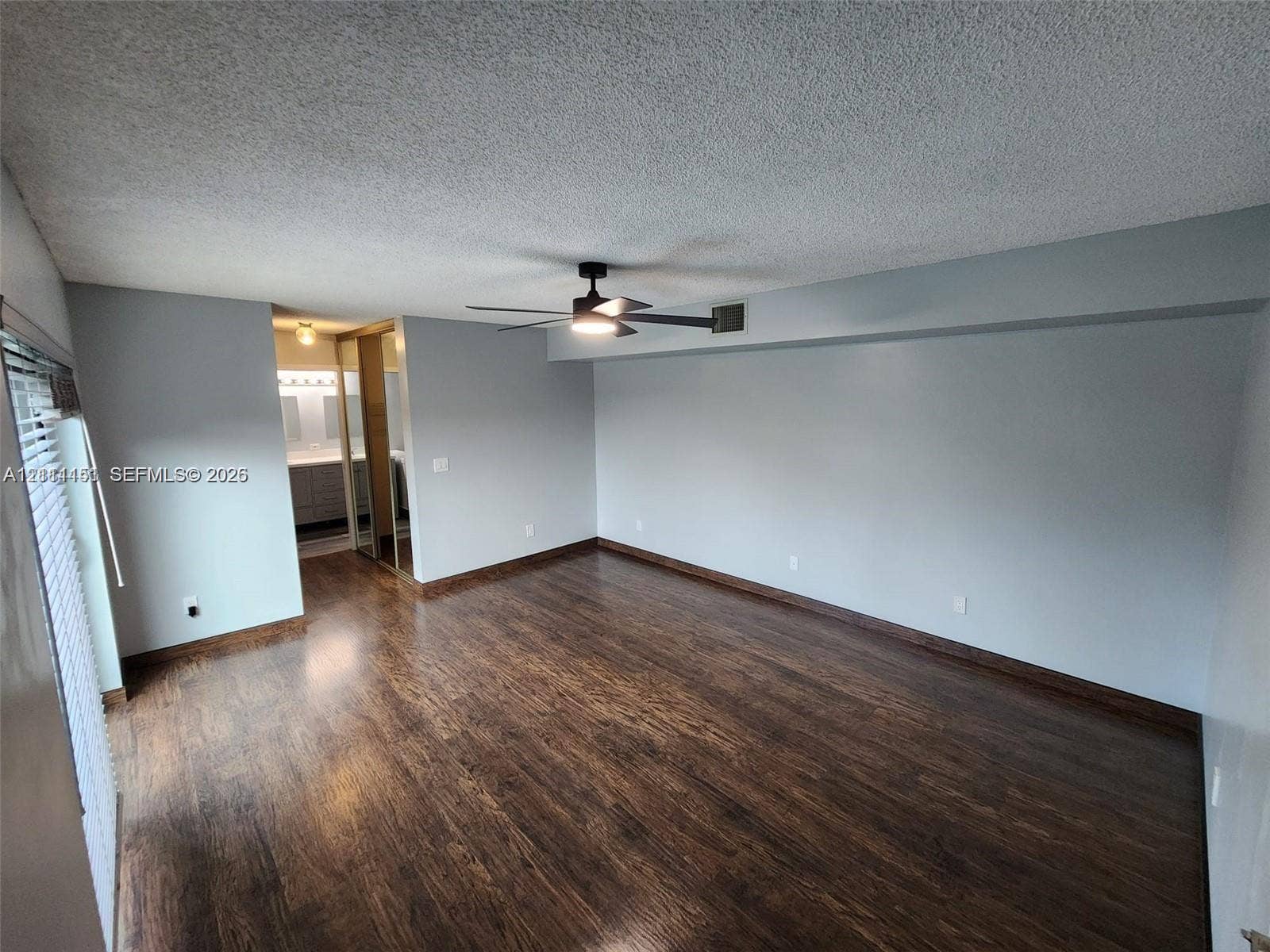 Room featuring wood-finish flooring, a ceiling fan with integrated lighting, and mirrored sliding closet doors