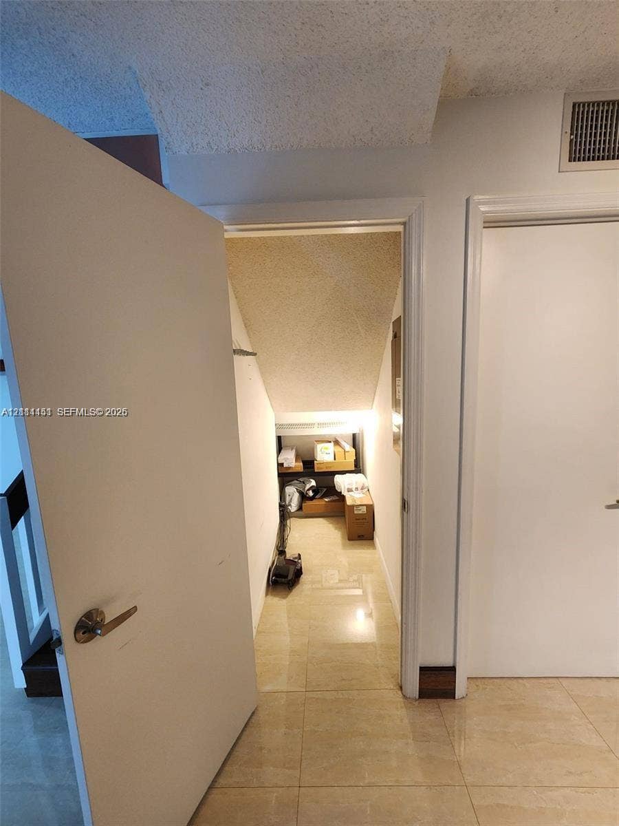Storage closet featuring tile flooring, smooth-finish door, and integrated shelving