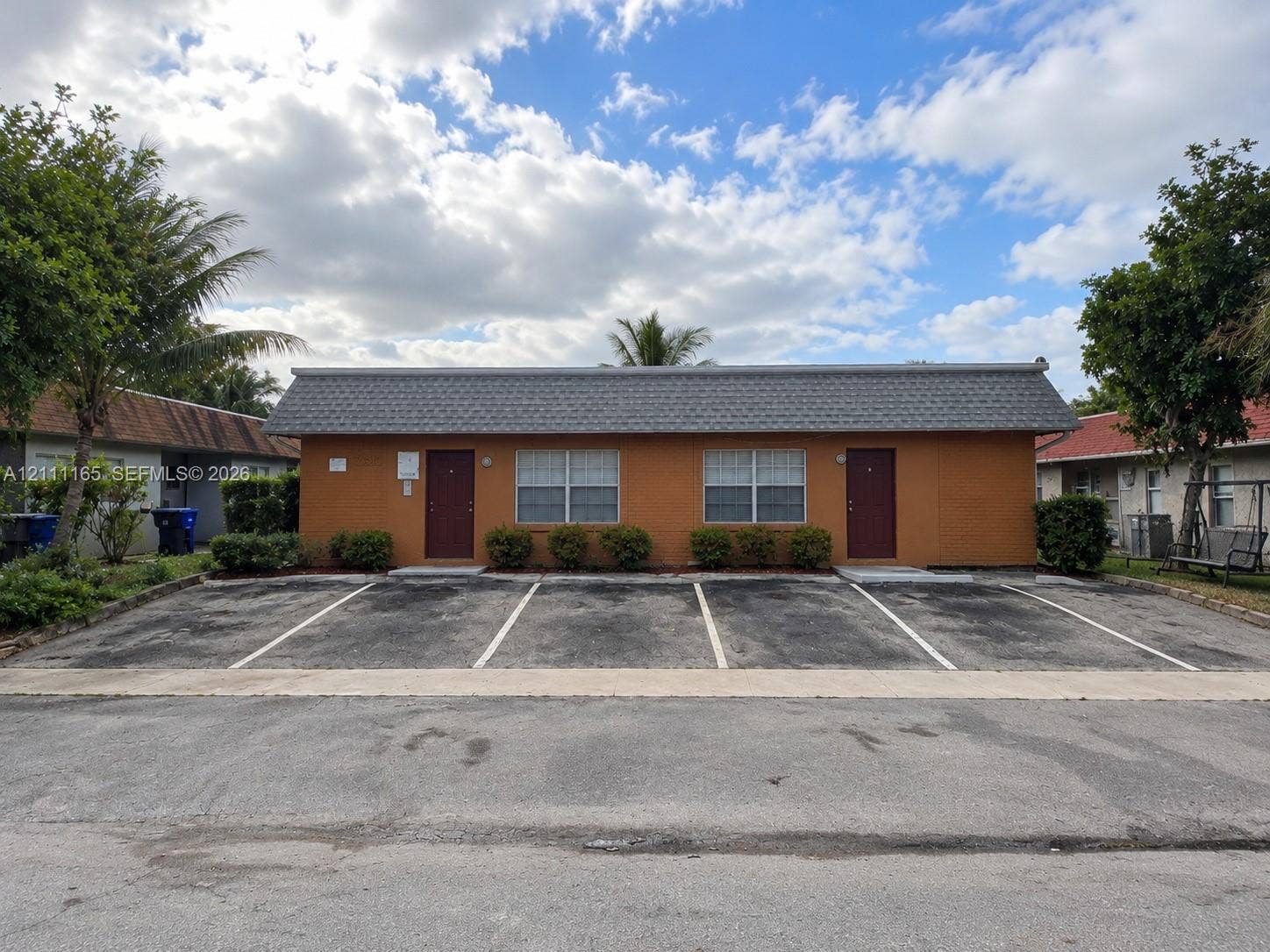 Exterior facade featuring a shingled roof, stucco finish, dedicated parking spaces.