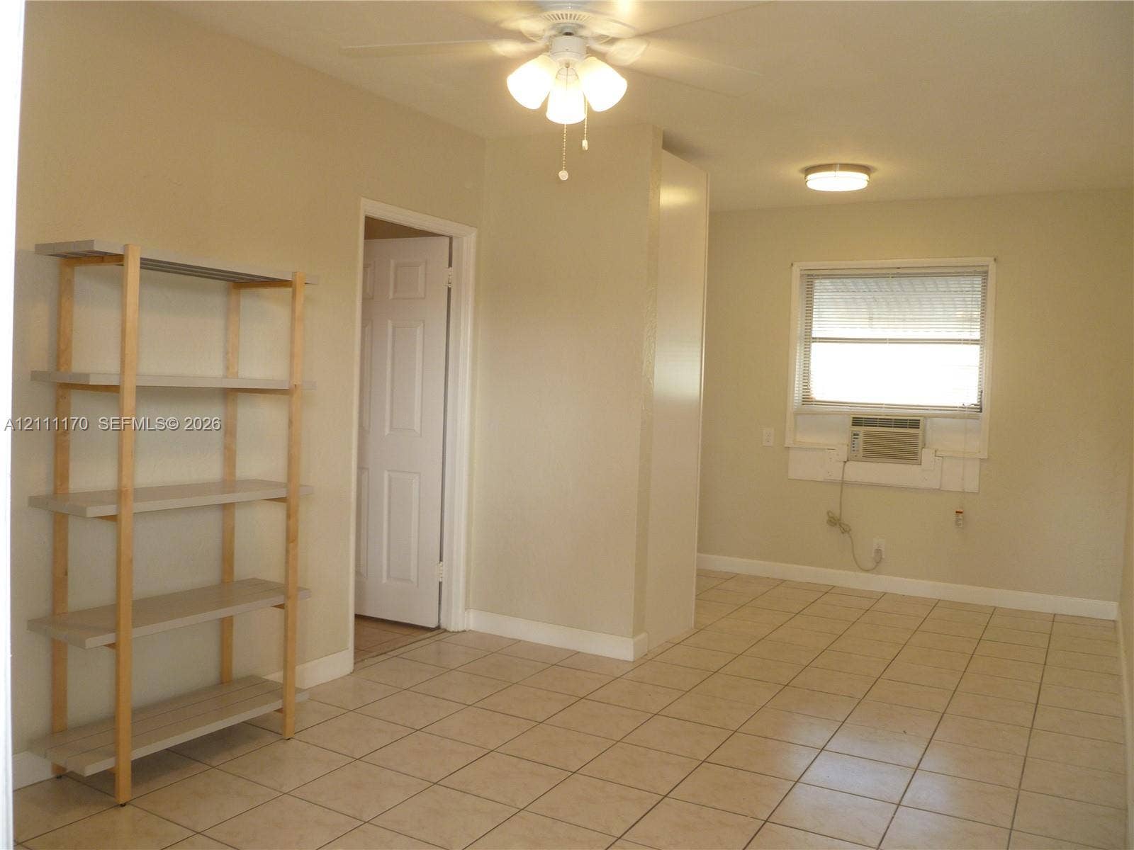 1005 N 18th Court, #5, Hollywood, Hollywood, FL 33020 Neutral-toned interior space featuring ceramic tile flooring, a multi-light ceiling fan, a flush-mount ceiling light fixture, and a window with a dedicated through-wall air conditioning unit