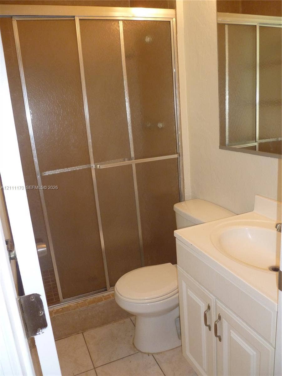 1005 N 18th Court, #5, Hollywood, Hollywood, FL 33020 Shower featuring a metal-framed sliding enclosure with textured glass, single-basin vanity with an integrated countertop, wall-mounted mirror, and tile flooring