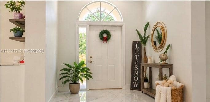 Foyer entrance featuring stone-finish flooring, a six-panel entry door with sidelights, and an arched transom window