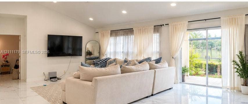 Vaulted ceilings, large-format polished tile flooring, recessed lighting, and expansive glass sliding doors