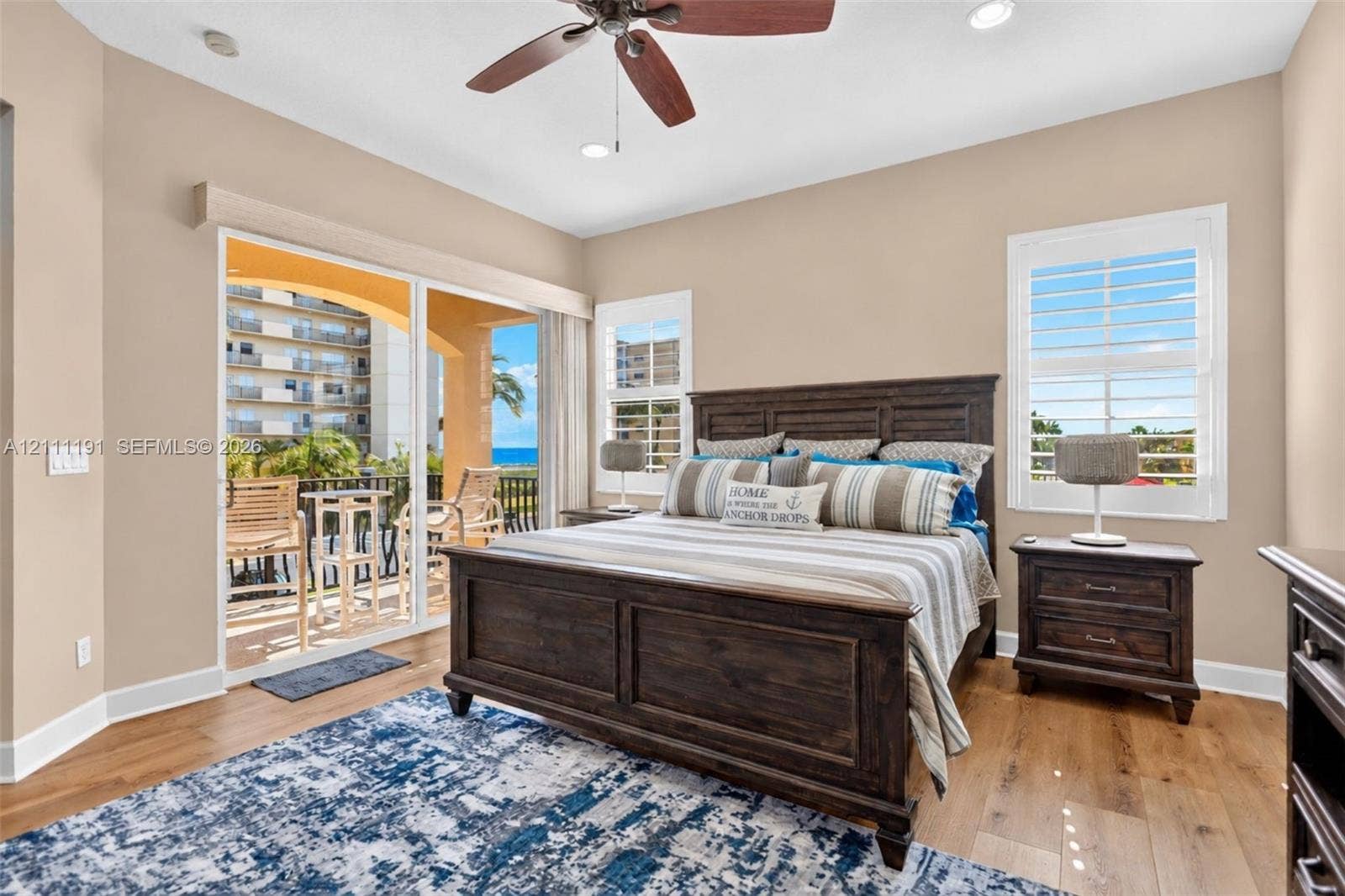 Bedroom featuring wood-finish flooring, plantation shutters, recessed lighting, a ceiling fan, and sliding glass doors opening to a balcony