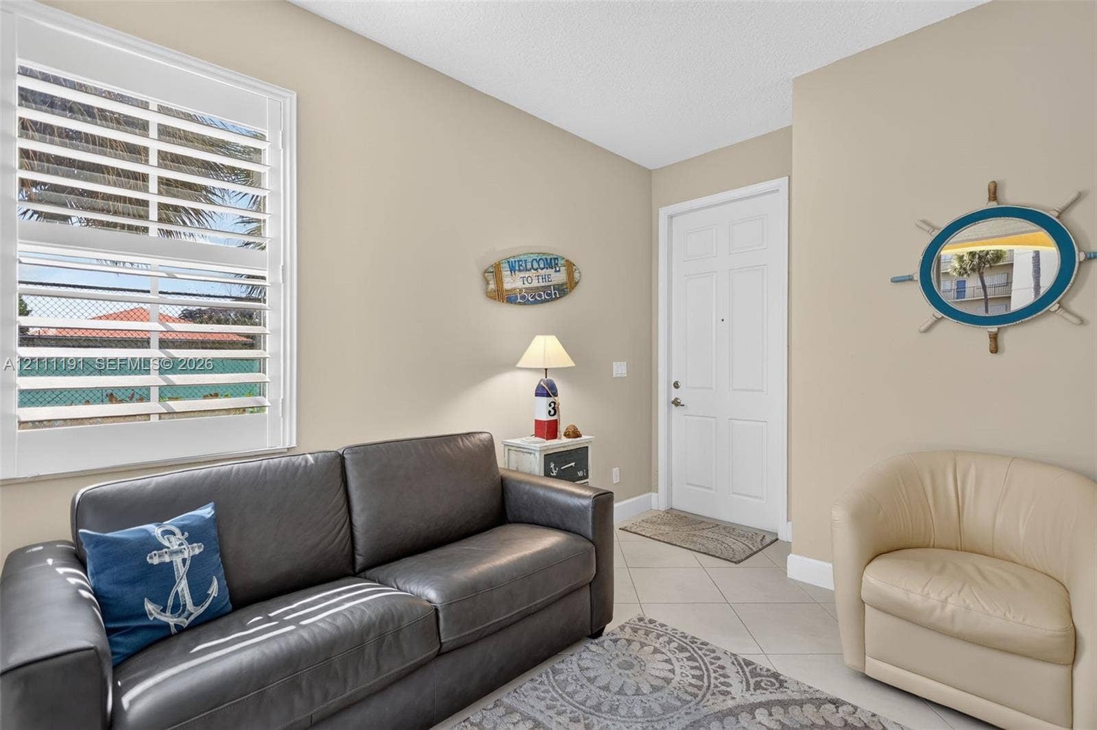 Extra sitting area/foyer on the first floor upon entering the front door. Neutral-toned interior featuring large-format ceramic tile flooring, adjustable white plantation shutters, and a six-panel door with brushed nickel hardware