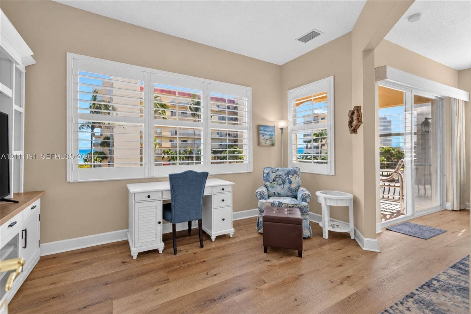 Sitting area off of PRIMARY BEDROOM. Wood-finish flooring, plantation shutters, entertainment center, and sliding glass doors