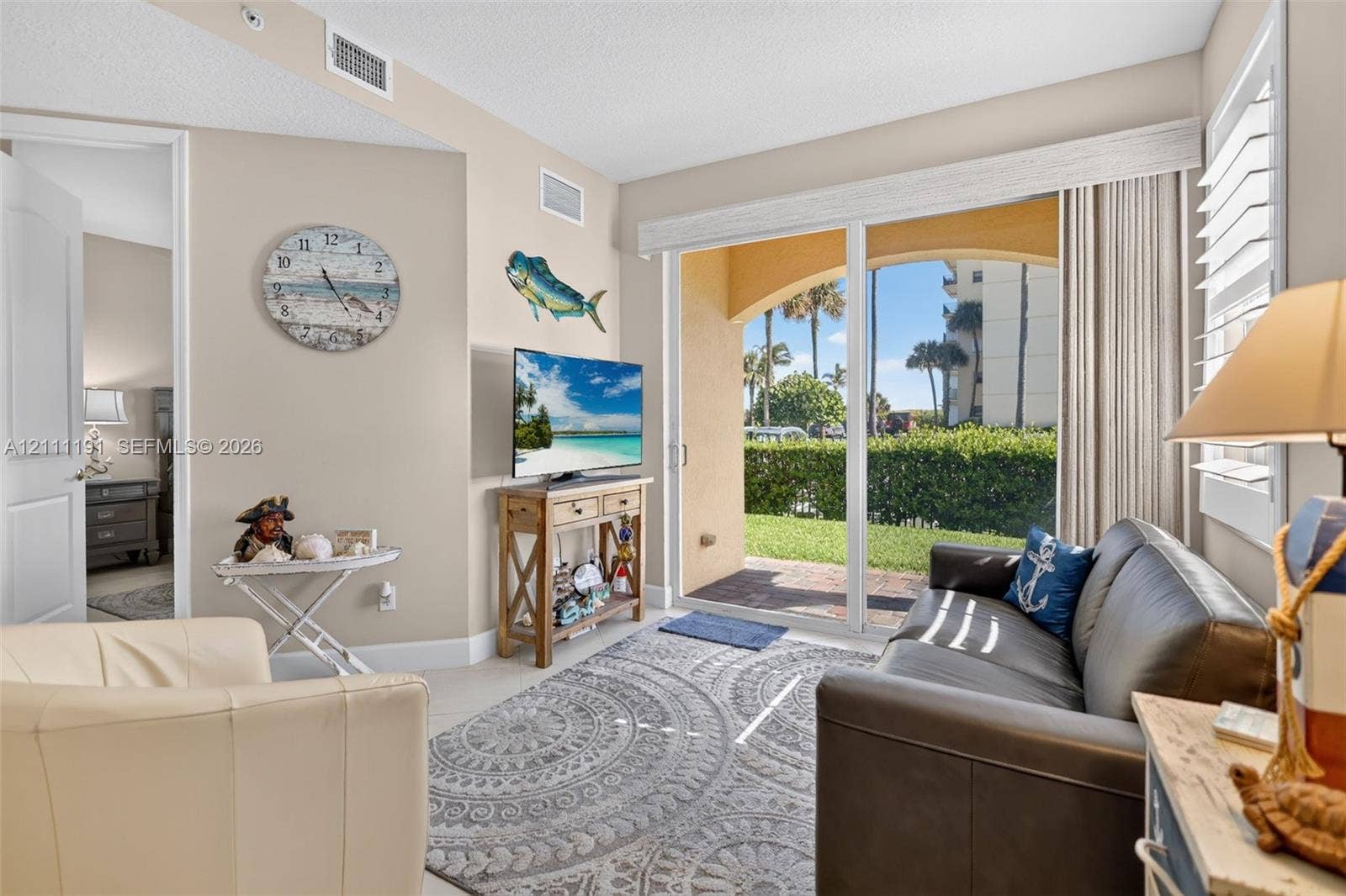 Extra sitting area/foyer on the first floor upon entering the front door. Neutral-toned interior featuring large-format ceramic tile flooring, adjustable white plantation shutters.