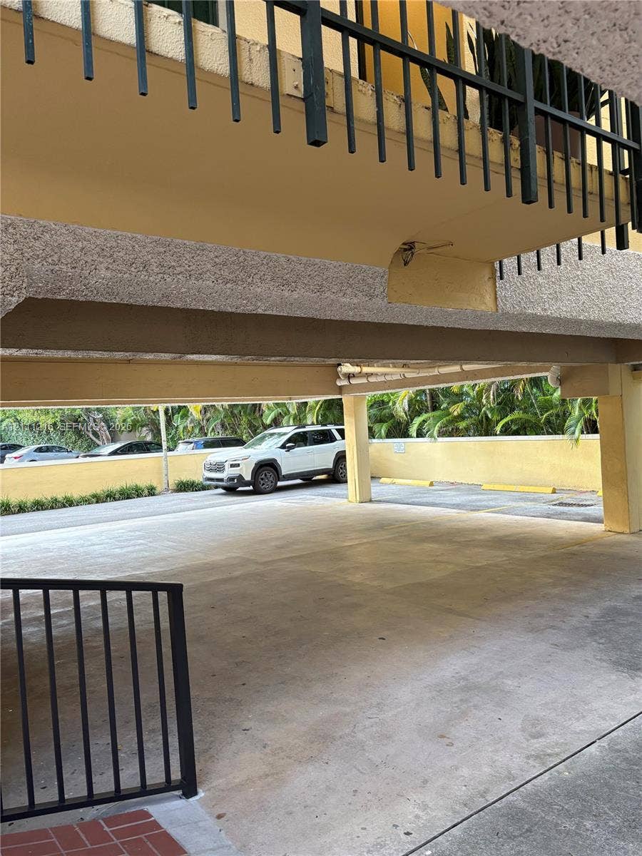 525 Coral Way, #303, Coral Gables, Coral Gables, FL 33134 Covered parking area featuring concrete flooring, structural support pillars, and black metal railings