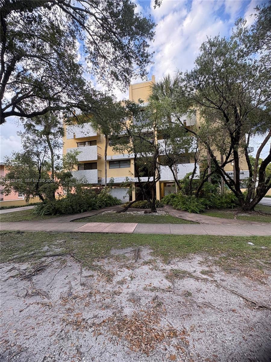 525 Coral Way, #303, Coral Gables, Coral Gables, FL 33134 Multi-story building exterior featuring concrete construction, white balcony railings, and mature canopy trees
