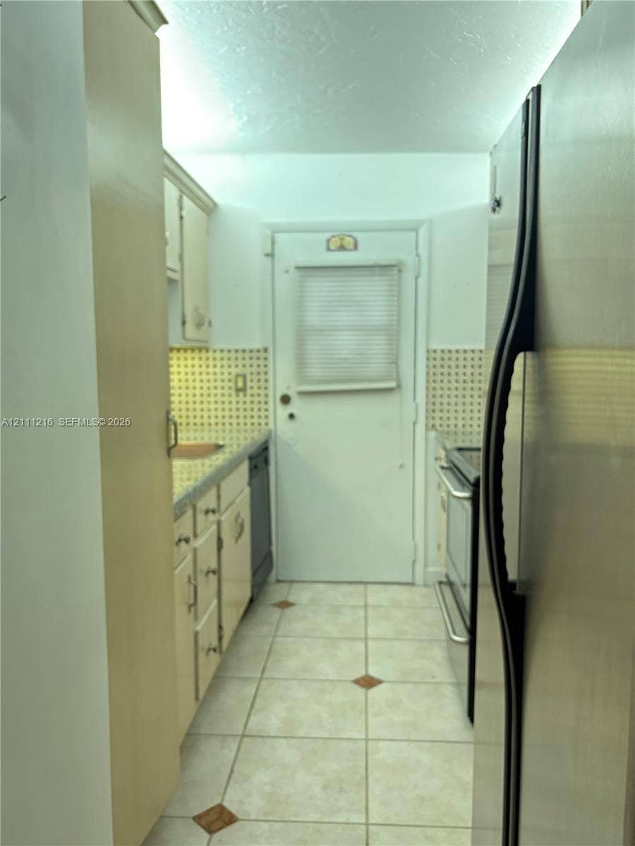525 Coral Way, #303, Coral Gables, Coral Gables, FL 33134 Galley kitchen featuring neutral cabinetry, stone-finish countertops, tile backsplash, tile flooring with decorative inlay, and stainless steel appliances
