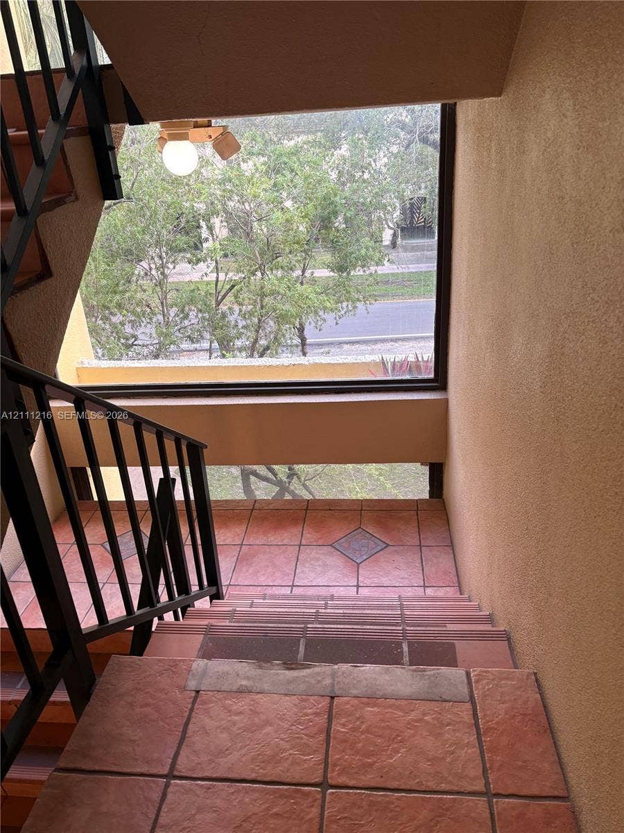 525 Coral Way, #303, Coral Gables, Coral Gables, FL 33134 Staircase featuring textured terracotta-toned tile flooring, diamond-patterned tile accents, and black metal railings