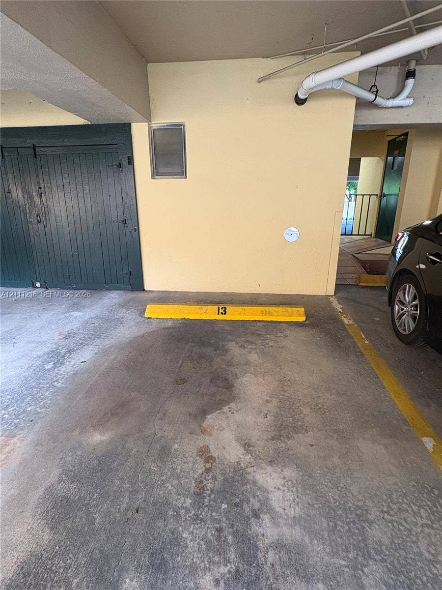 525 Coral Way, #303, Coral Gables, Coral Gables, FL 33134 Covered parking space featuring a concrete surface, dedicated yellow wheel stop, and nearby built-in storage unit