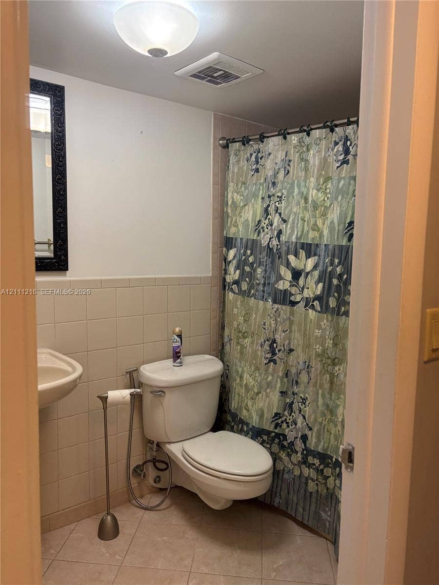 525 Coral Way, #303, Coral Gables, Coral Gables, FL 33134 Bathroom featuring tile wall cladding, wall-mounted porcelain sink, ceramic tile flooring, and a flush-mount ceiling light fixture