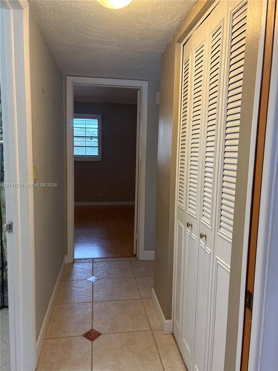 525 Coral Way, #303, Coral Gables, Coral Gables, FL 33134 Hallway featuring light-colored tile flooring with decorative inlay accents and white louvered bi-fold closet doors