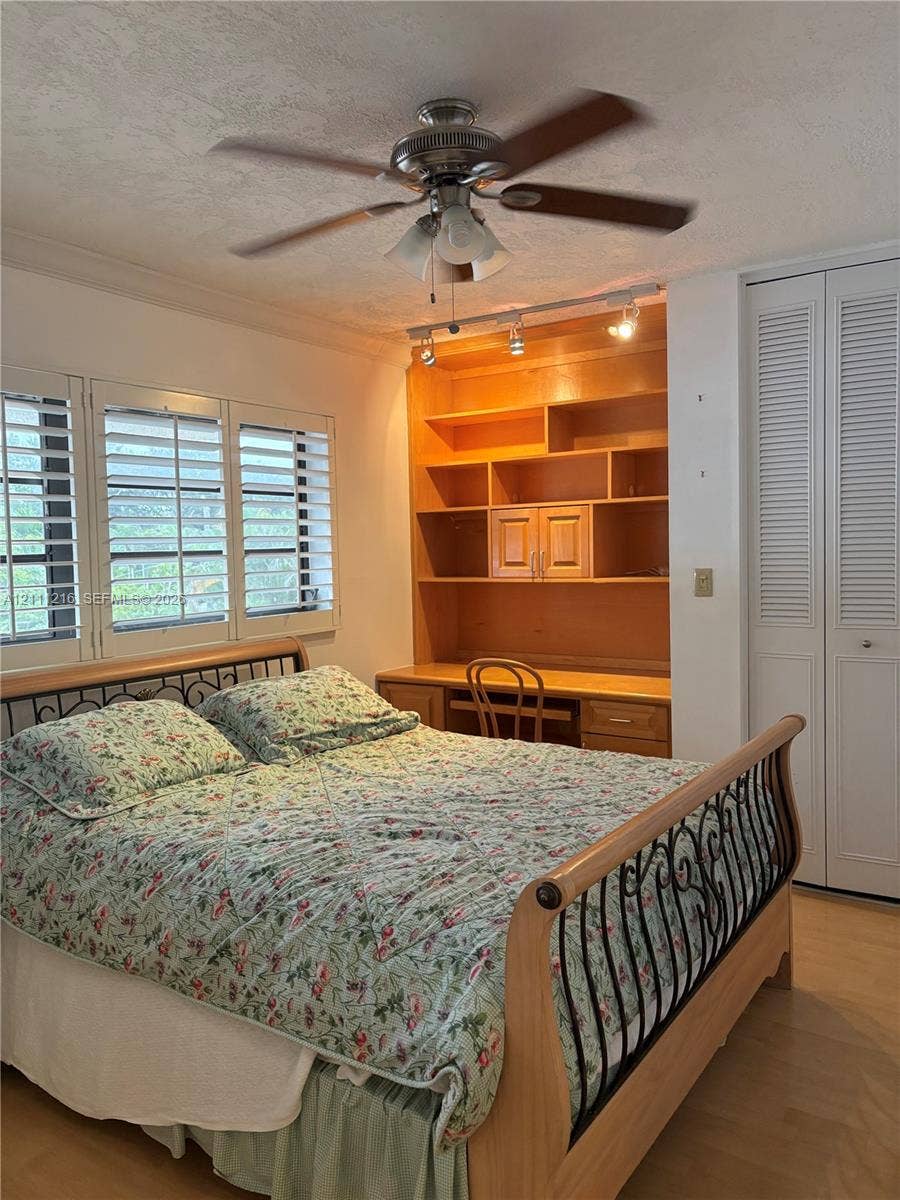 525 Coral Way, #303, Coral Gables, Coral Gables, FL 33134 Built-in wood shelving with integrated desk, white louvered-style closet doors, wood-finish flooring, plantation shutters, and ceiling fan with integrated lighting