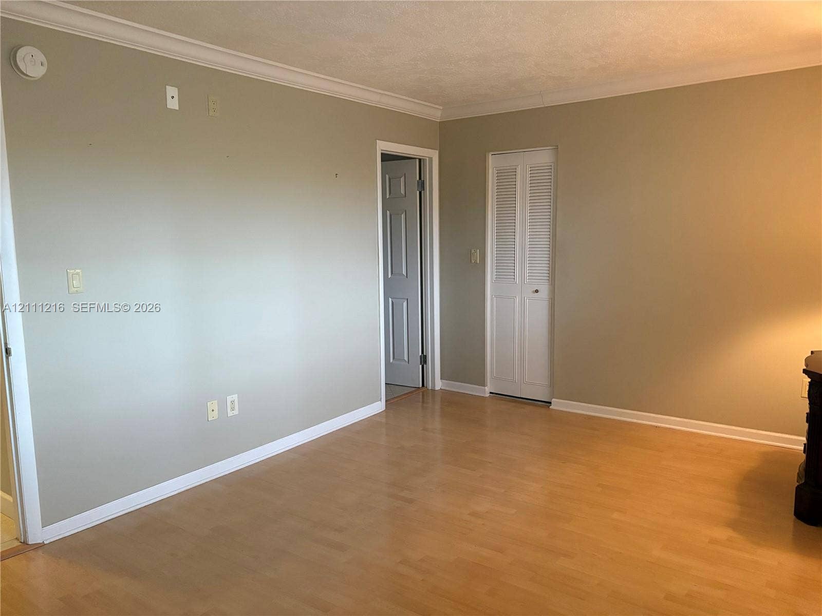 525 Coral Way, #303, Coral Gables, Coral Gables, FL 33134 Interior space featuring wood-finish flooring, neutral wall paint, white crown molding, and a louvered bi-fold closet door