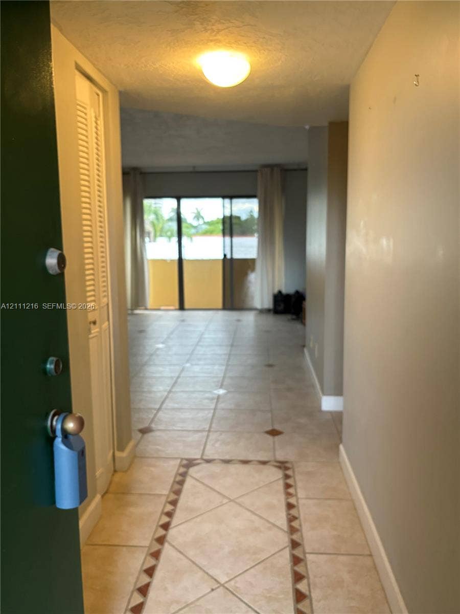 525 Coral Way, #303, Coral Gables, Coral Gables, FL 33134 Entryway featuring neutral tile flooring with a decorative geometric border, louvered bi-fold closet doors, and flush-mount ceiling lighting