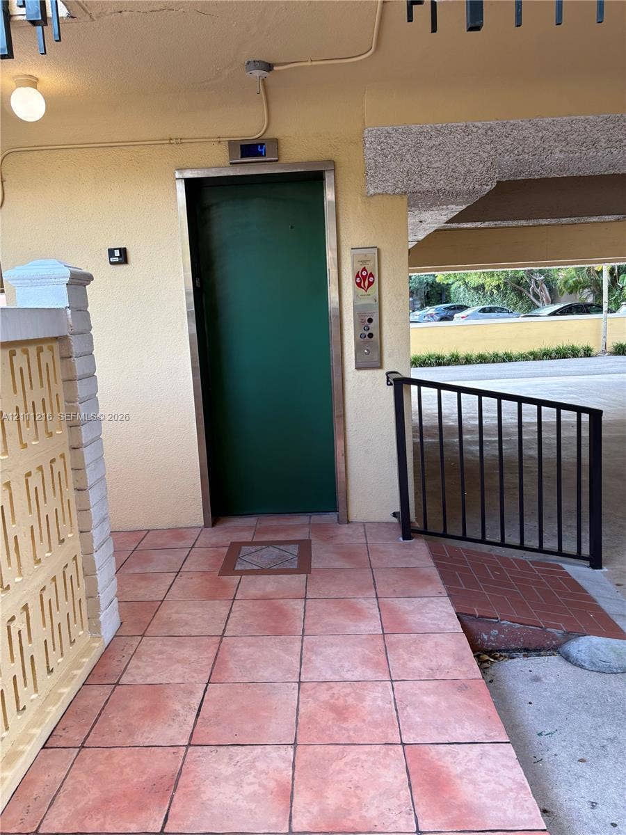 525 Coral Way, #303, Coral Gables, Coral Gables, FL 33134 Elevator entrance featuring a stainless steel door frame, tile flooring, wall-mounted control panel, and a paved ramp with a black metal handrail
