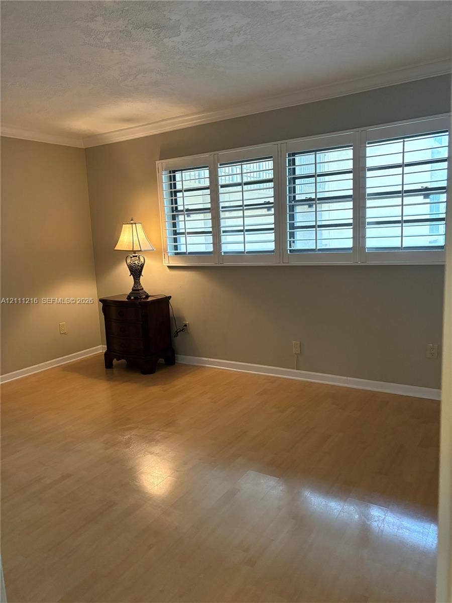 525 Coral Way, #303, Coral Gables, Coral Gables, FL 33134 Interior space featuring wood-finish flooring, multi-pane windows with integrated white plantation shutters, and crown molding