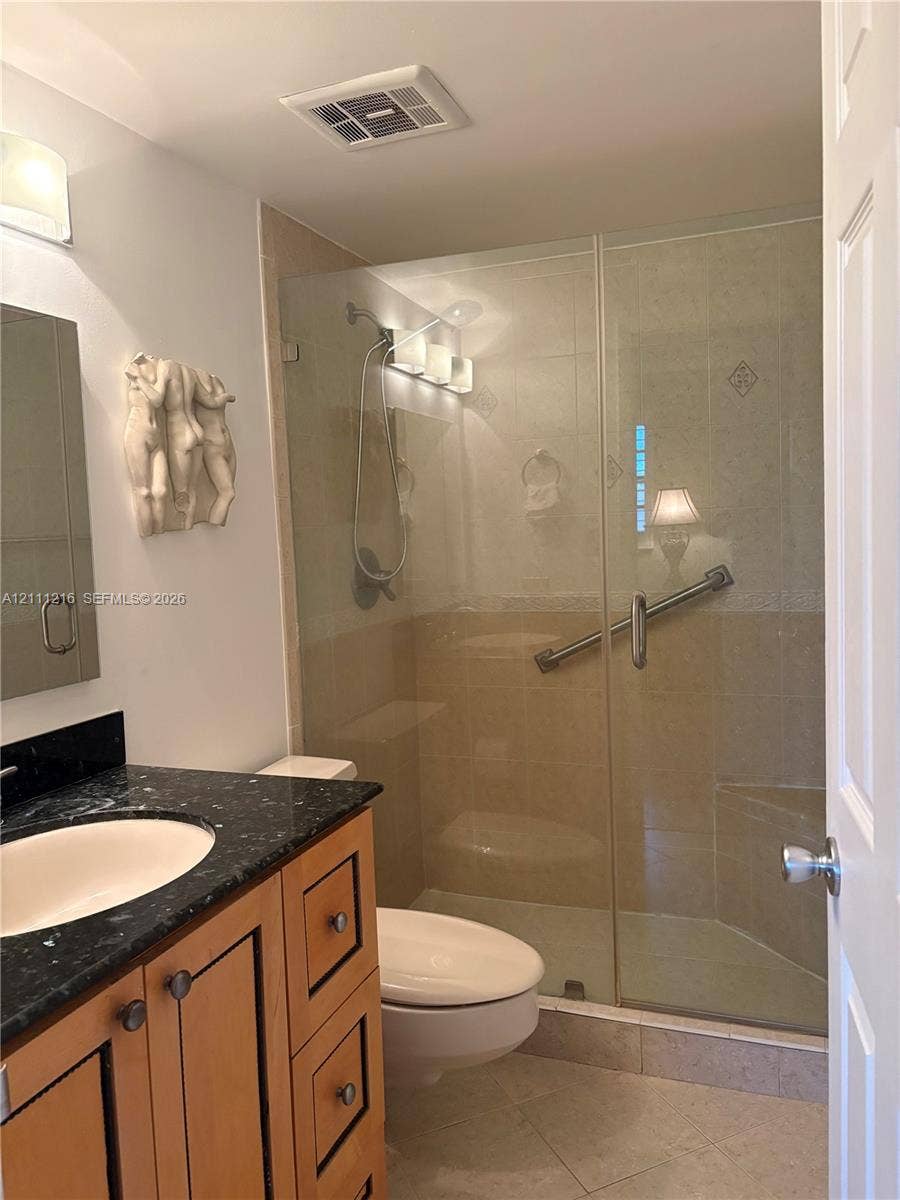 525 Coral Way, #303, Coral Gables, Coral Gables, FL 33134 Bathroom featuring a vanity with a stone countertop and an undermount sink, paired with a glass-enclosed shower with tiled surround and an integrated bench