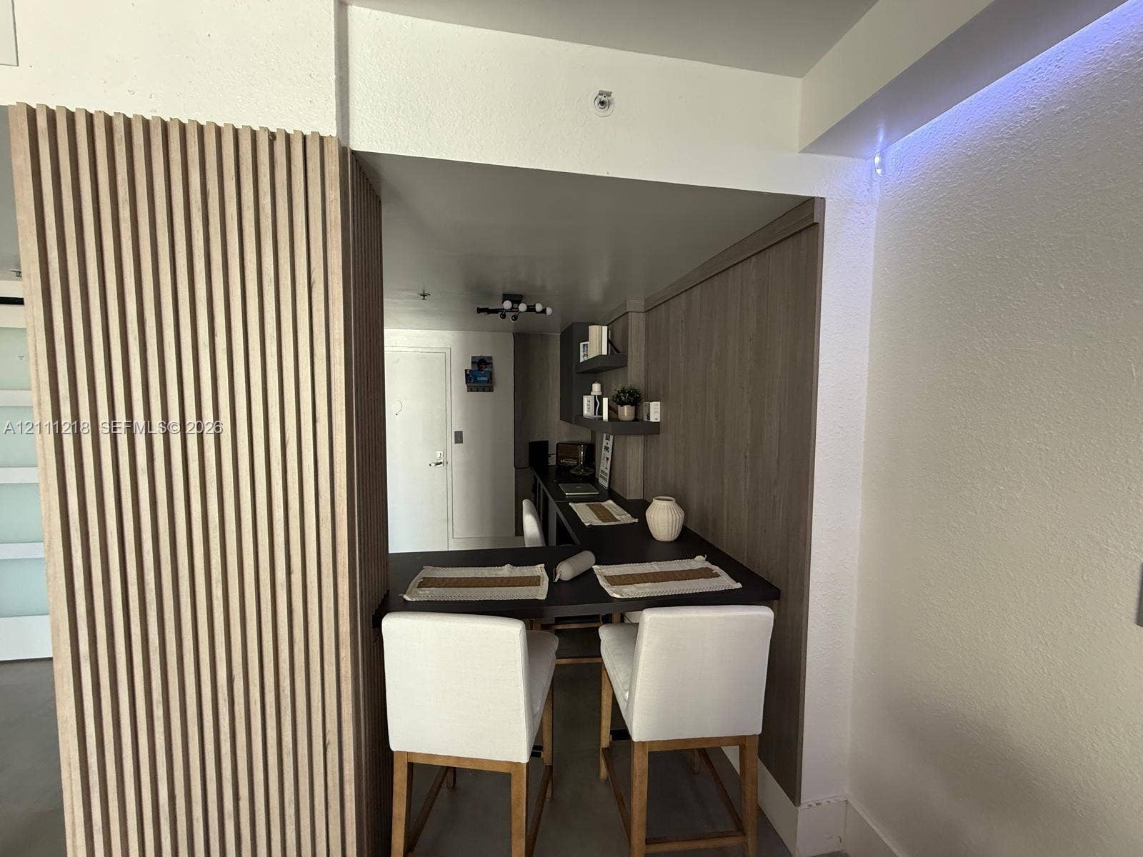 Vertical wood slat paneling, integrated wood-finish cabinetry, built-in recessed counter, and modern multi-bulb ceiling fixture