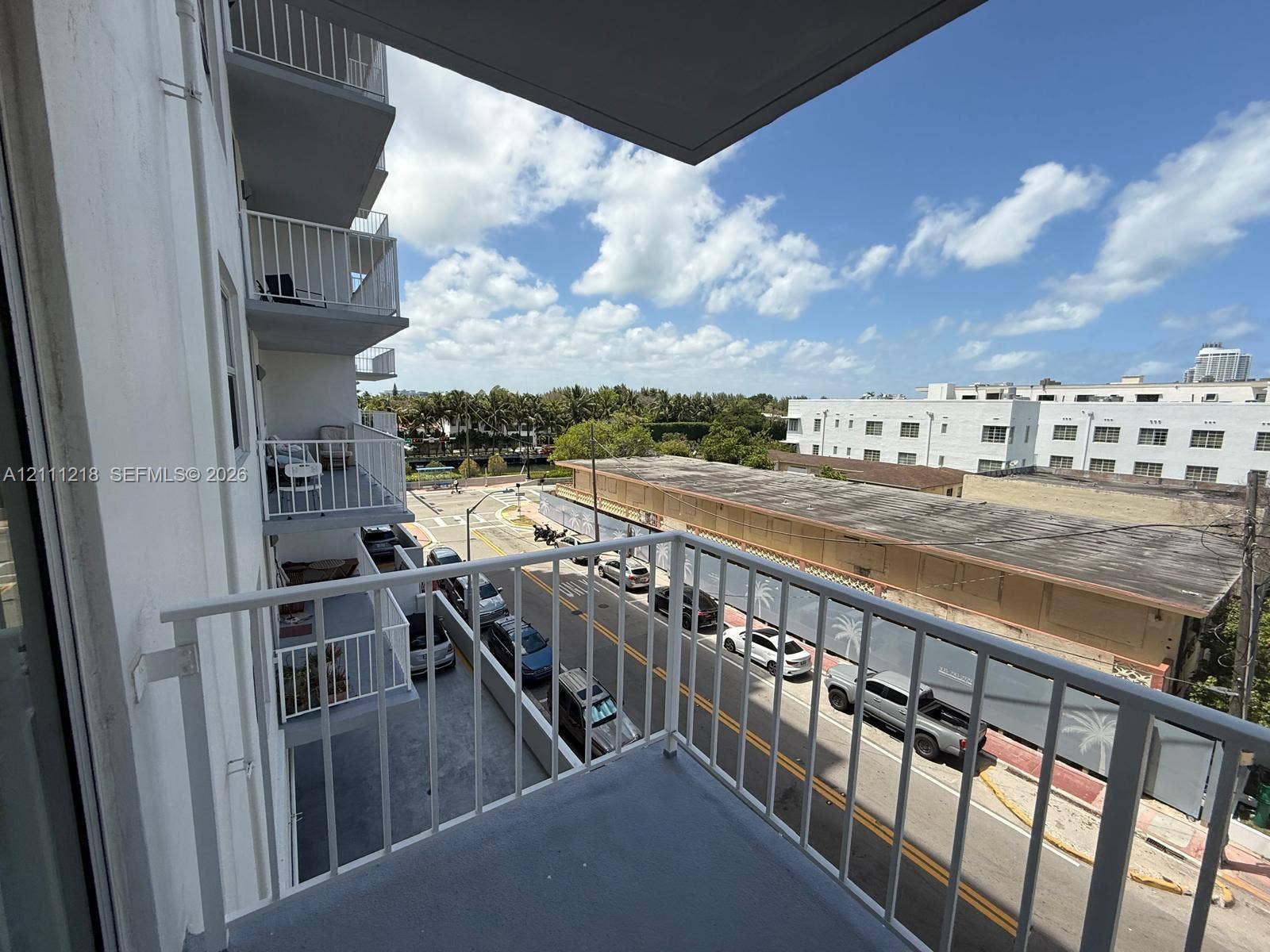 Private exterior balcony featuring white vertical railings and concrete flooring