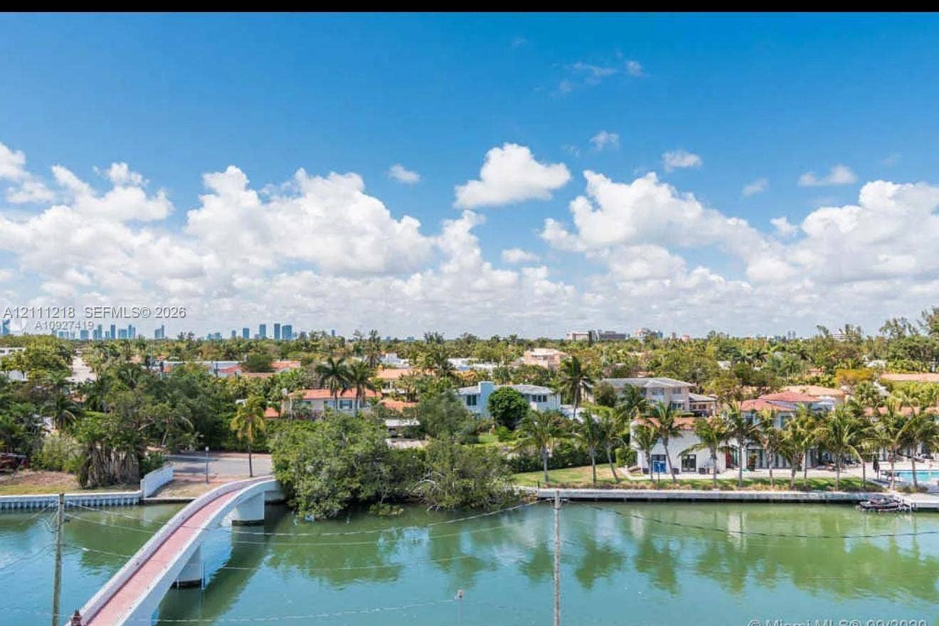 Waterfront setting featuring a concrete arch bridge, bulkhead seawall, and tropical vegetation