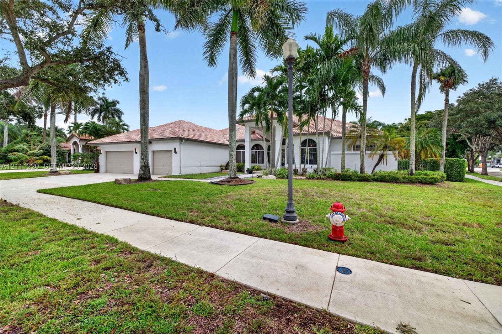 134 Dockside Terrace, Weston, FL 33327 Single-story residence featuring a tile roof, light-toned exterior finish, attached two-car garage, concrete driveway, and mature palm landscaping