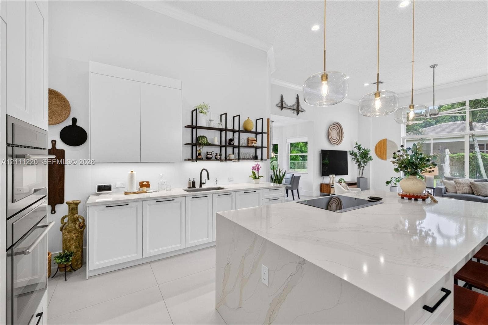 134 Dockside Terrace, Weston, FL 33327 Kitchen featuring a large central island with a stone-surface countertop, high-gloss white cabinetry, built-in stainless steel double wall ovens, matte black hardware, and glass pendant lighting