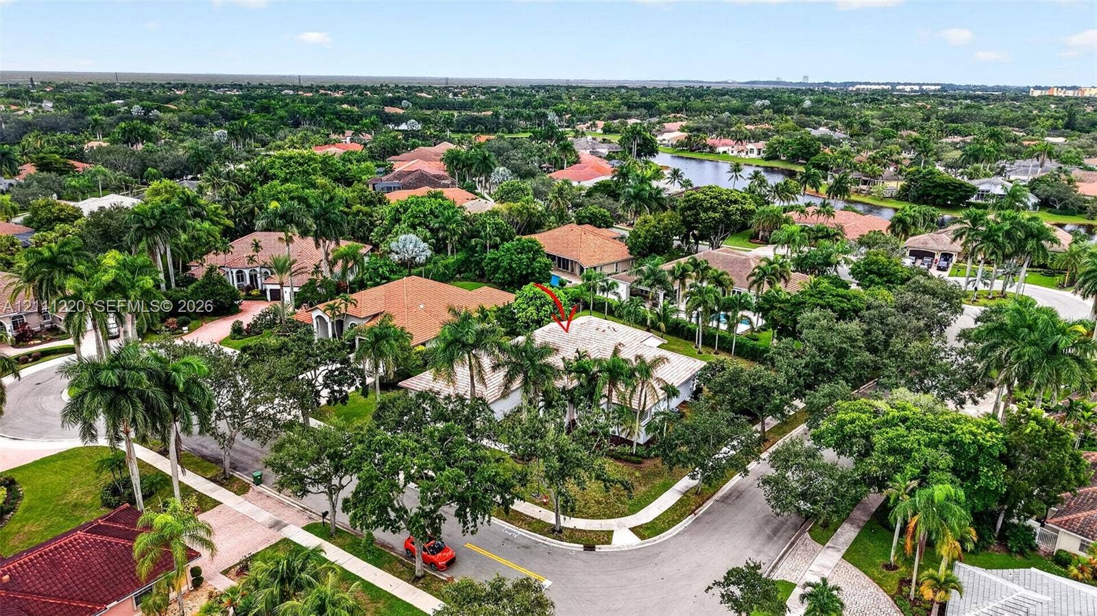 134 Dockside Terrace, Weston, FL 33327 Aerial perspective of a corner lot residence featuring a tile roof, paved driveway, established perimeter landscaping, and mature palm trees