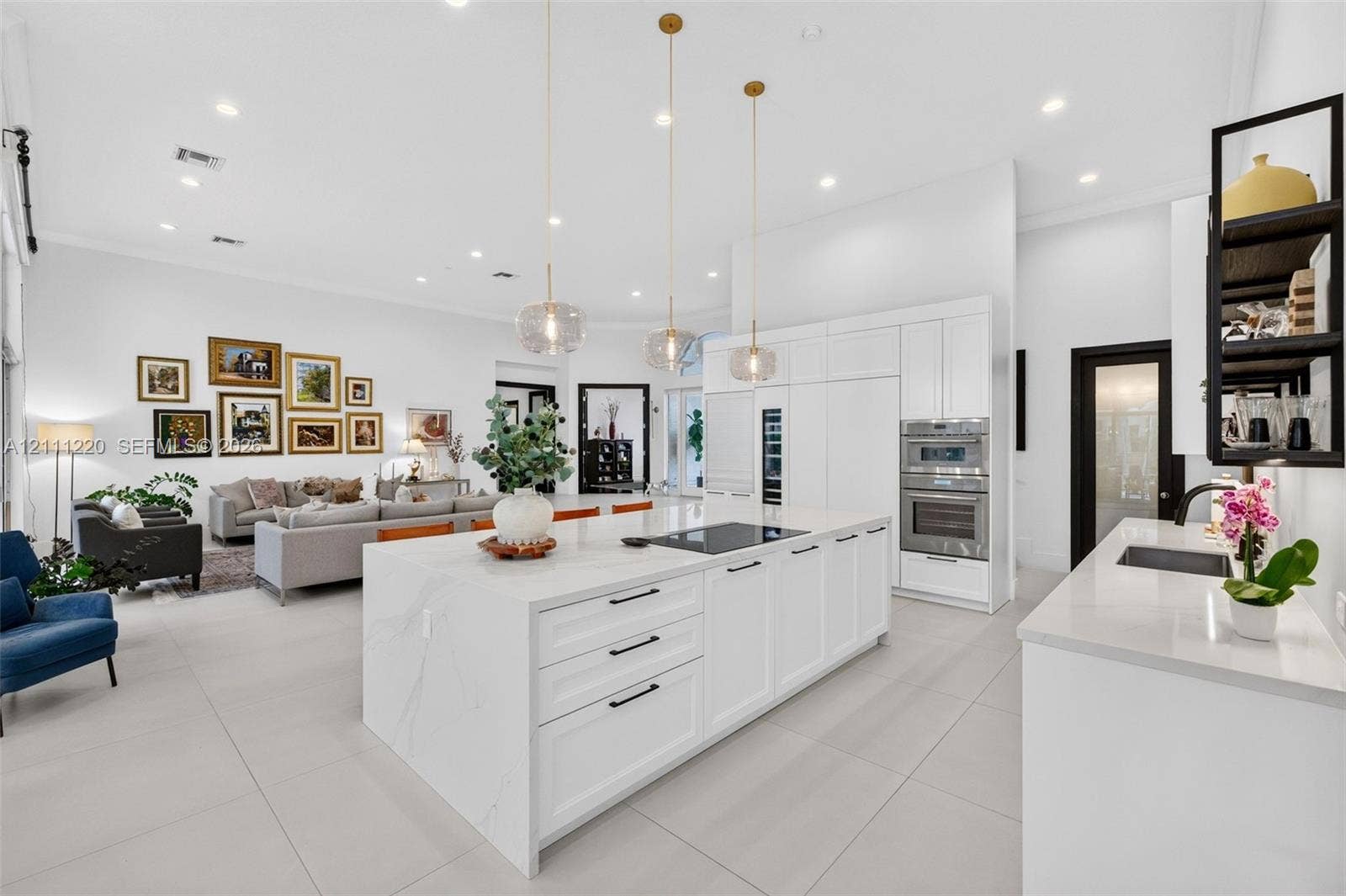 134 Dockside Terrace, Weston, FL 33327 Kitchen featuring a large central island with quartz surfacing, white shaker-style cabinetry, stainless steel double wall ovens, three glass pendant light fixtures, and neutral oversized tile flooring