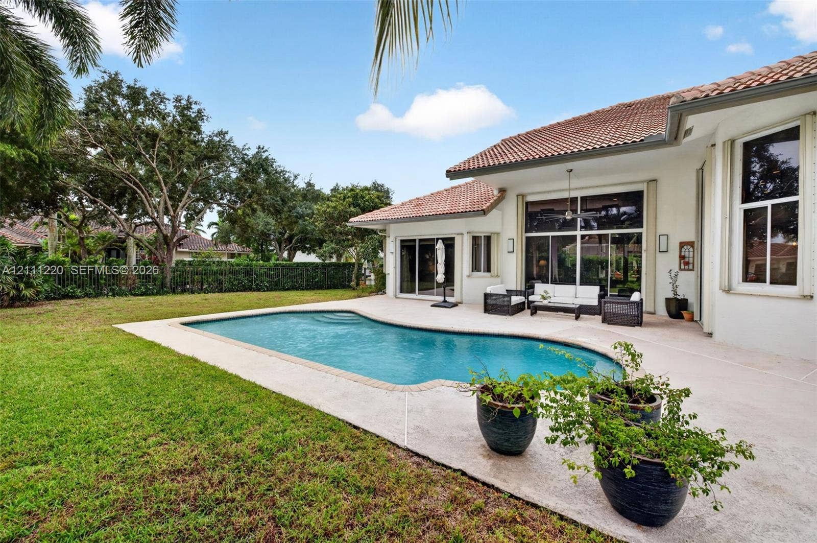 134 Dockside Terrace, Weston, FL 33327 Rear exterior featuring a swimming pool, expansive concrete patio, manicured lawn, tile roof, and floor-to-ceiling glass doors