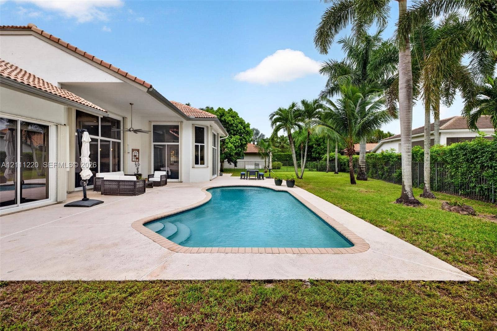 134 Dockside Terrace, Weston, FL 33327 Expansive concrete patio featuring a built-in pool with masonry coping, mature palms, and manicured lawn