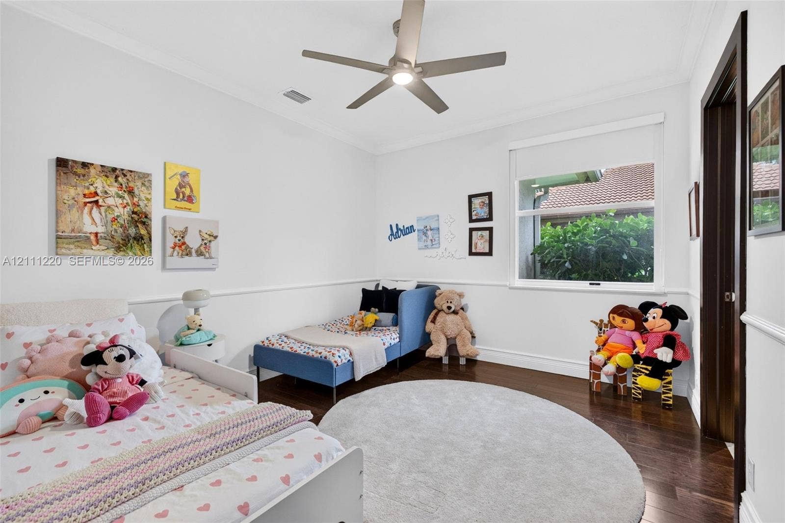 134 Dockside Terrace, Weston, FL 33327 Bedroom interior featuring dark wood-finish flooring, crown molding, chair rail trim, a multi-blade ceiling fan with integrated lighting, and a single-pane window