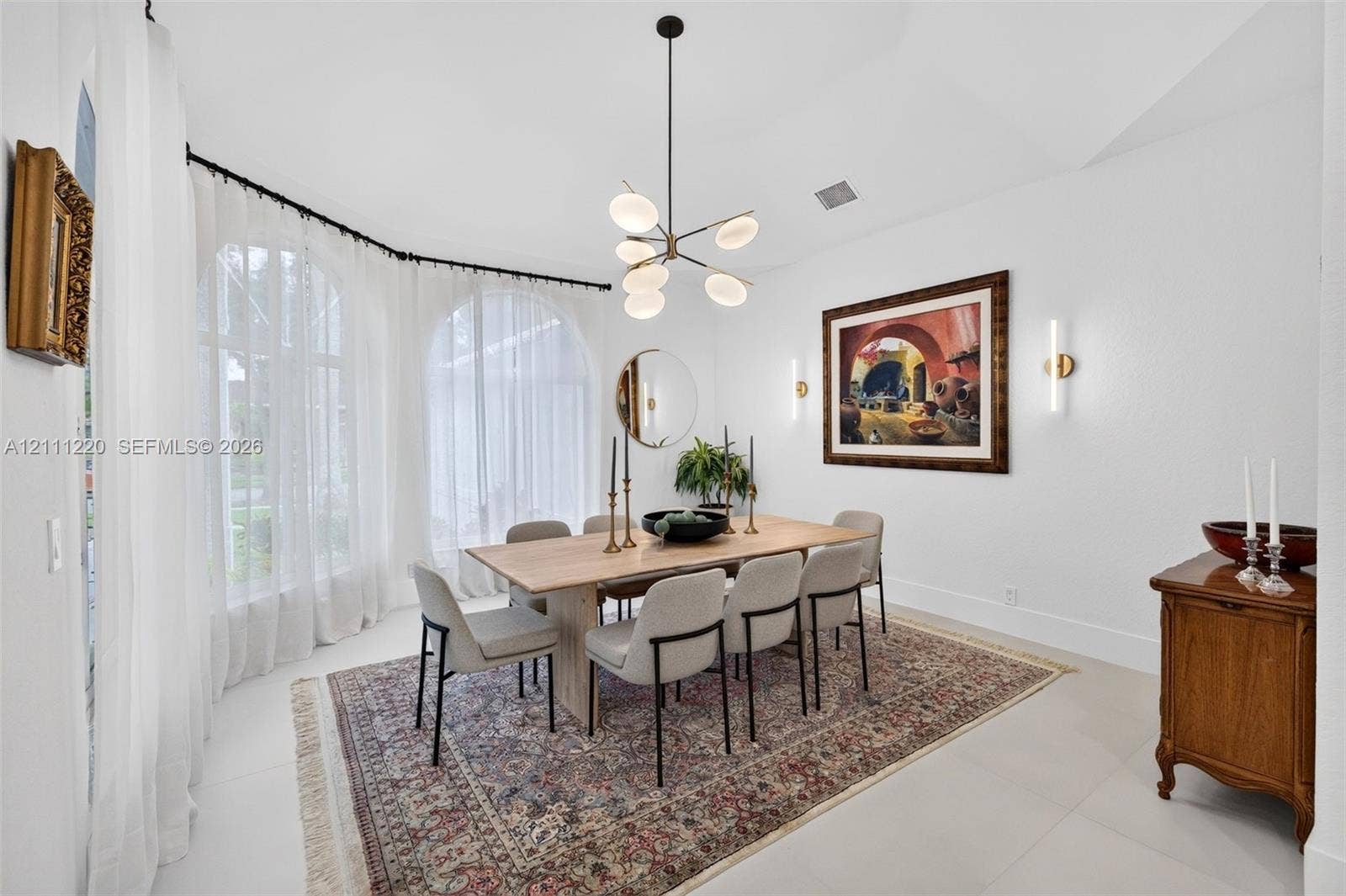 134 Dockside Terrace, Weston, FL 33327 Dining area featuring arched windows, vaulted ceiling, multi-arm chandelier, and wall-mounted linear lighting